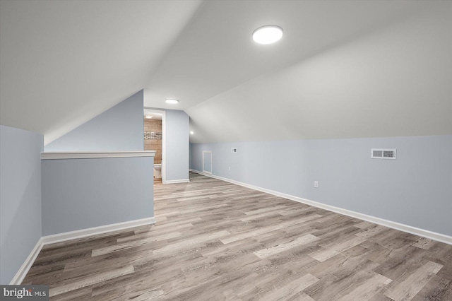 bonus room with baseboards, visible vents, vaulted ceiling, and wood finished floors