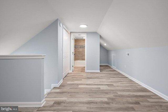 bonus room with baseboards, vaulted ceiling, and wood finished floors