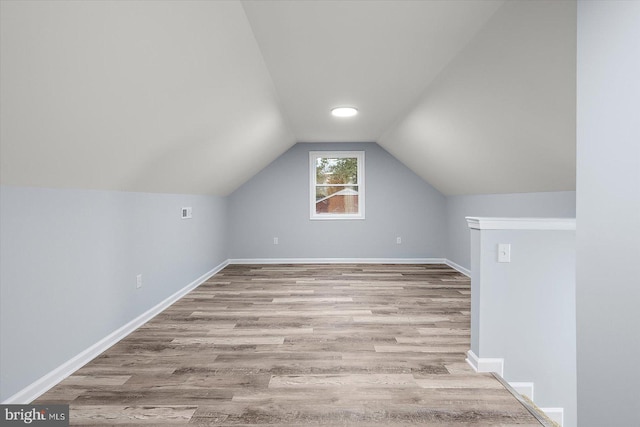 additional living space with lofted ceiling, wood finished floors, and baseboards