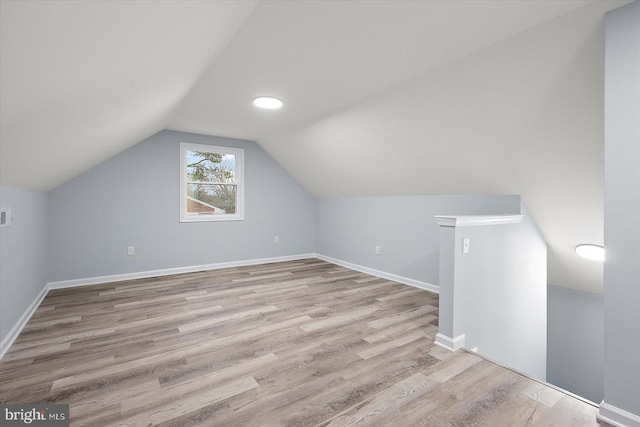 additional living space with lofted ceiling, baseboards, and wood finished floors