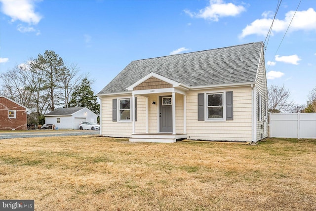 bungalow-style house featuring a front yard, roof with shingles, and fence