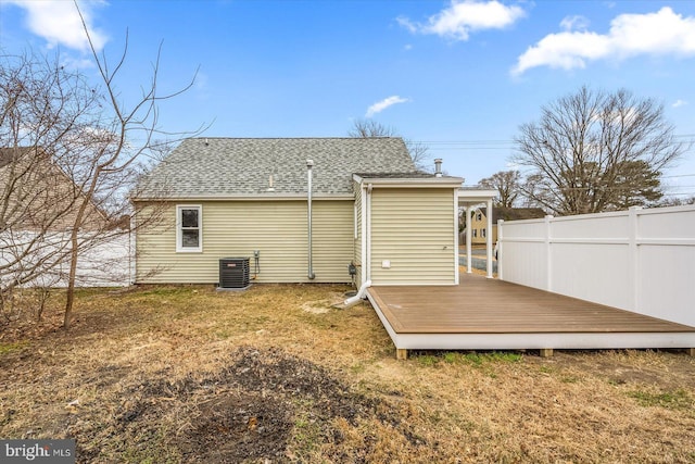 back of house with a shingled roof, a wooden deck, and fence