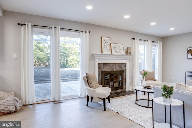 living area with recessed lighting, baseboards, wood finished floors, and a high end fireplace