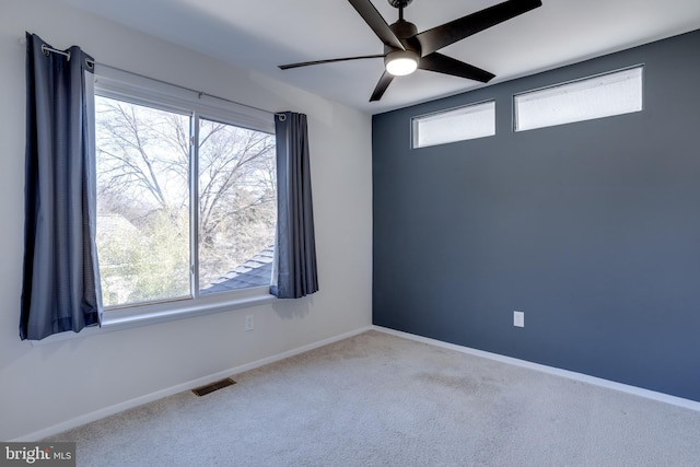 carpeted empty room with visible vents, ceiling fan, and baseboards