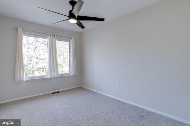 carpeted empty room with a ceiling fan, visible vents, and baseboards