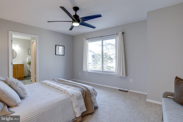 bedroom featuring light carpet, ceiling fan, baseboards, and connected bathroom