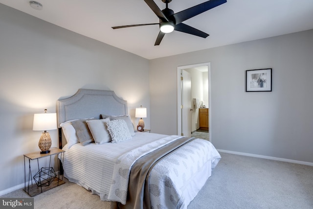 bedroom featuring light carpet, ensuite bathroom, a ceiling fan, and baseboards