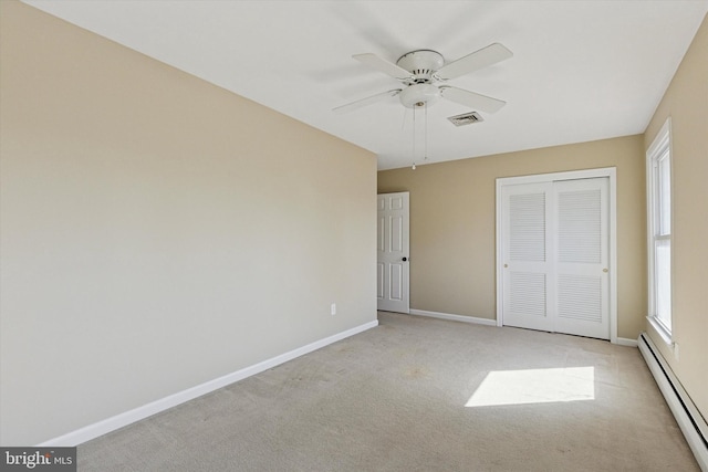 unfurnished bedroom with a closet, light carpet, baseboards, and baseboard heating