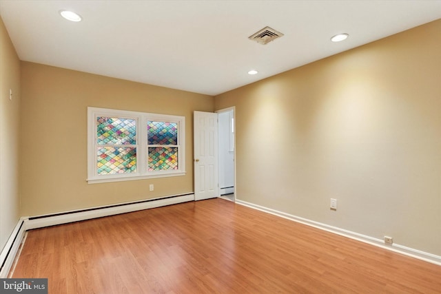 spare room with a baseboard radiator, visible vents, a baseboard heating unit, wood finished floors, and baseboards