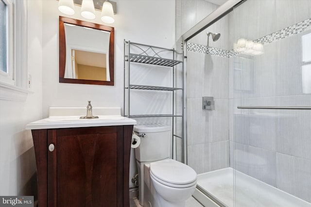 full bathroom featuring tiled shower, vanity, and toilet