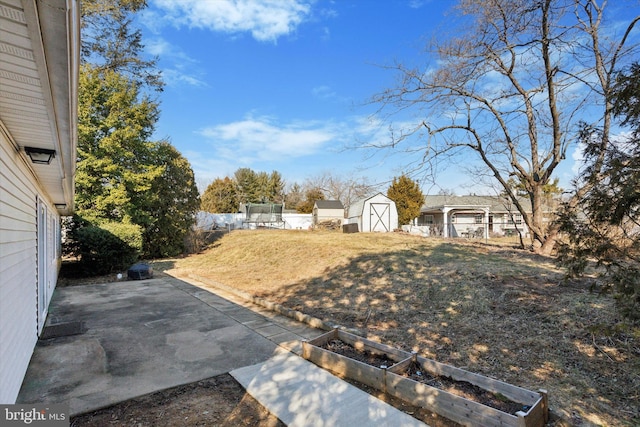 view of yard featuring a patio, a storage unit, fence, a garden, and an outdoor structure