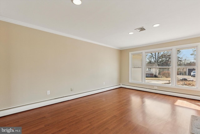 empty room with ornamental molding, a baseboard radiator, visible vents, and wood finished floors