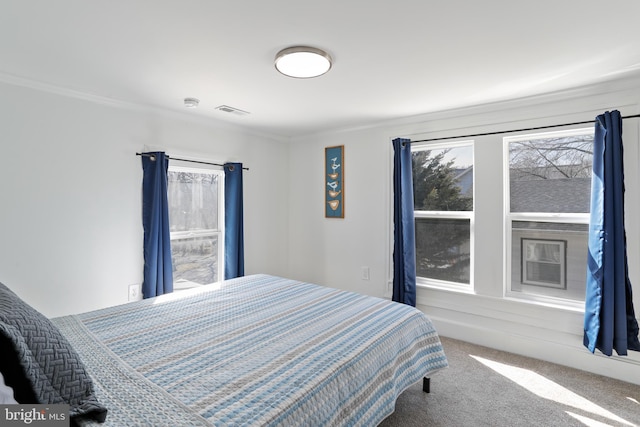 carpeted bedroom with visible vents and crown molding