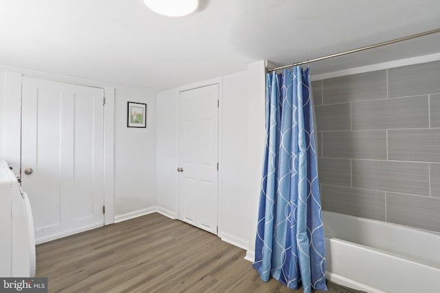 full bathroom featuring baseboards, washer / clothes dryer, wood finished floors, and shower / tub combo with curtain