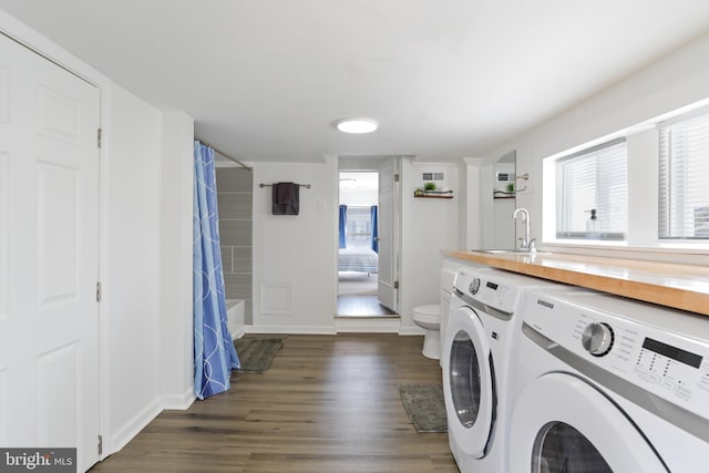 washroom with laundry area, baseboards, dark wood-type flooring, washing machine and dryer, and a sink