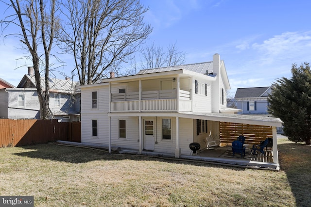 rear view of property with metal roof, a patio, fence, a yard, and a chimney