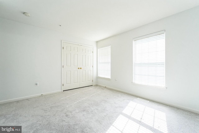 spare room featuring carpet, visible vents, and baseboards