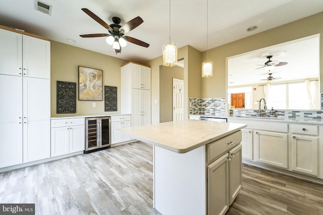 kitchen with wine cooler, visible vents, light wood-style flooring, backsplash, and a sink