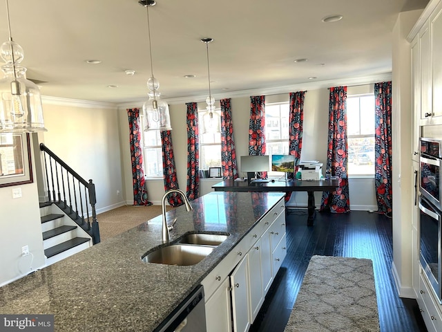 kitchen with crown molding, white cabinetry, dark stone counters, and a sink