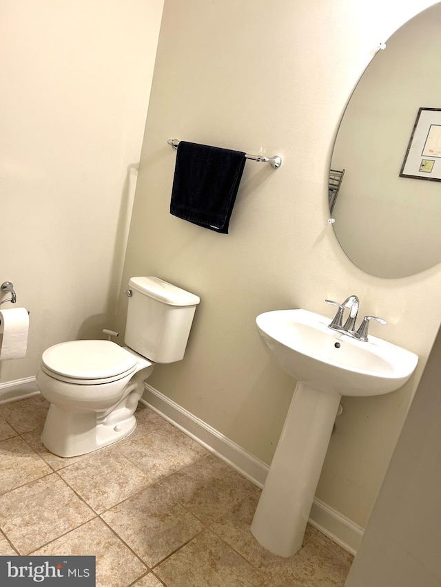 half bath featuring toilet, tile patterned flooring, and baseboards