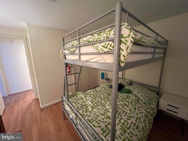 bedroom featuring baseboard heating, wood finished floors, and baseboards