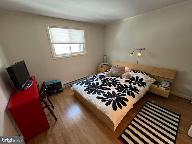 bedroom with baseboards, baseboard heating, and wood finished floors