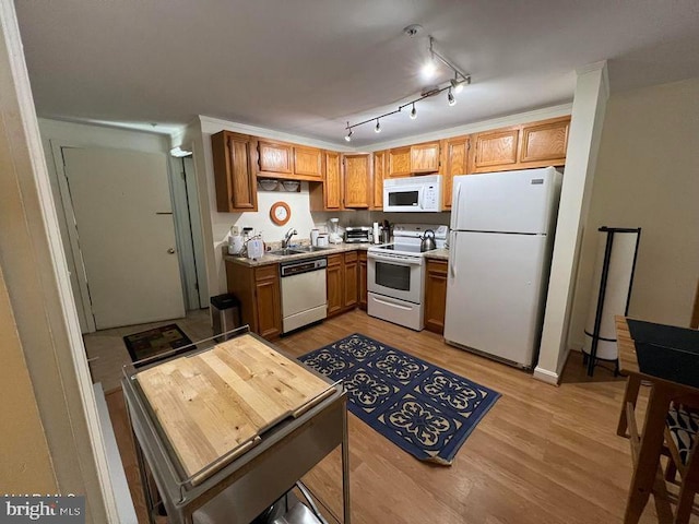 kitchen featuring brown cabinets, light countertops, light wood-style flooring, a sink, and white appliances