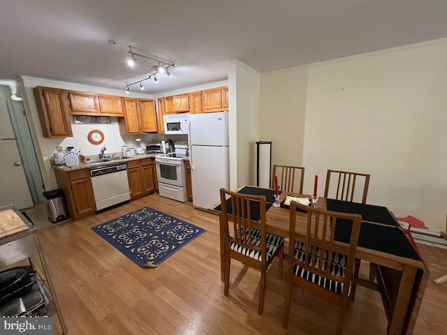 kitchen with white appliances, brown cabinets, light countertops, crown molding, and light wood-type flooring