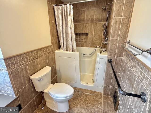 bathroom featuring toilet, a wainscoted wall, visible vents, tile walls, and shower / bath combo