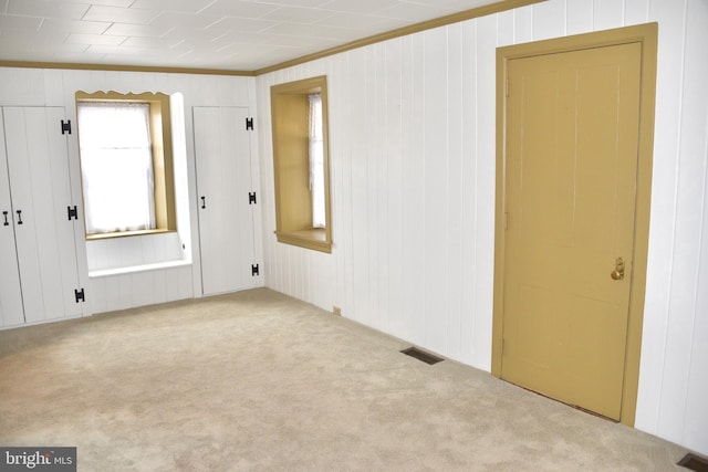 carpeted empty room with visible vents and crown molding