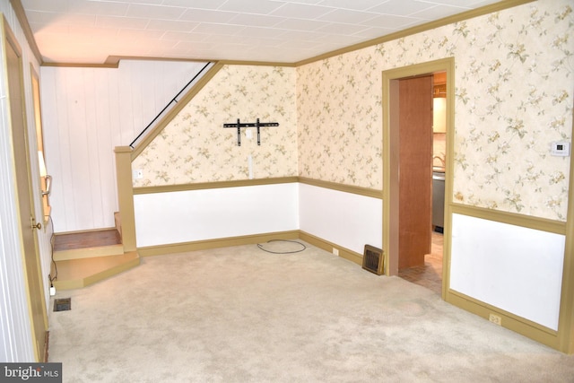 carpeted spare room featuring stairs, visible vents, and wallpapered walls