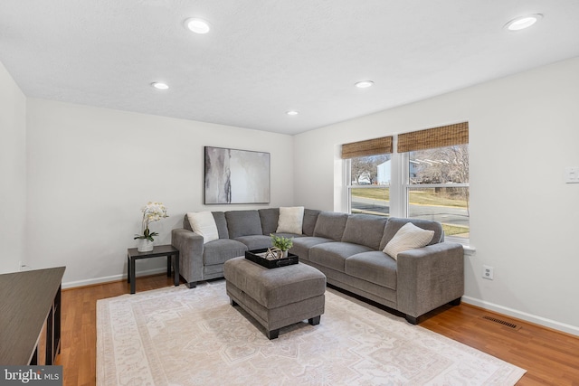 living room with recessed lighting, visible vents, baseboards, and light wood-style flooring