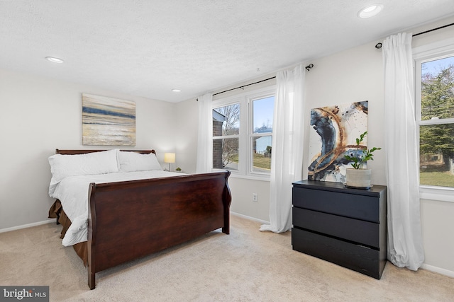 bedroom with light carpet, a textured ceiling, and baseboards