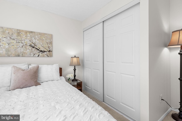 carpeted bedroom with a closet and baseboards