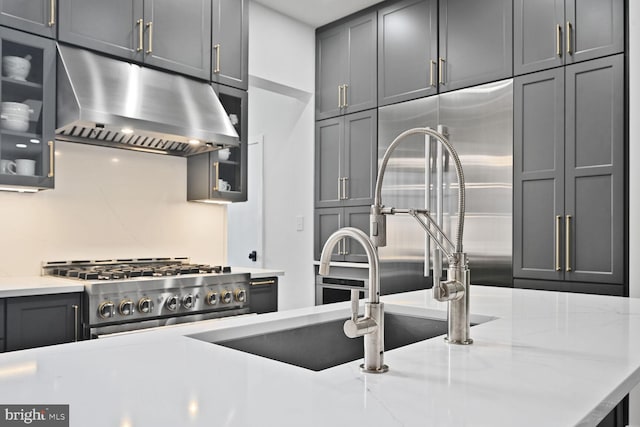 kitchen featuring range, glass insert cabinets, light stone counters, gray cabinets, and under cabinet range hood