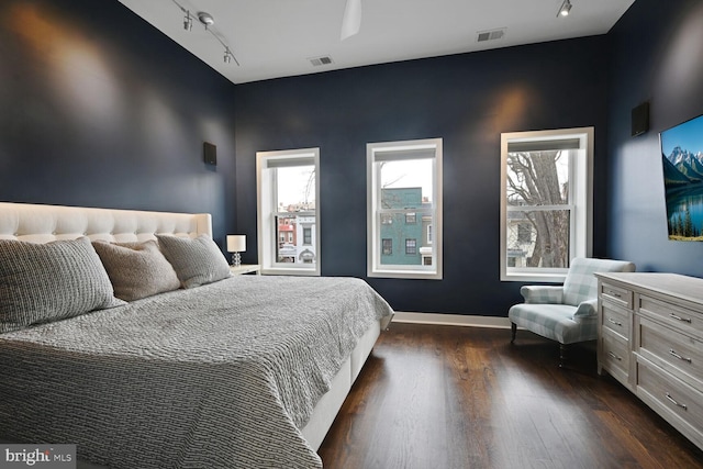 bedroom featuring multiple windows, visible vents, and dark wood finished floors