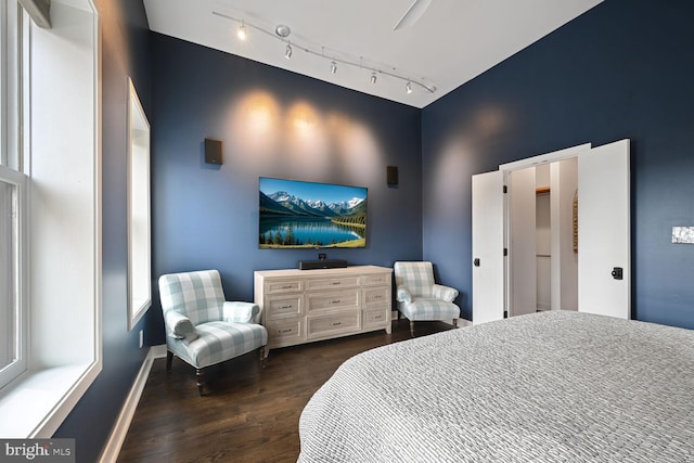 bedroom with rail lighting, baseboards, and wood finished floors