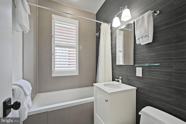 full bathroom featuring tiled shower / bath combo, tile walls, toilet, and vanity