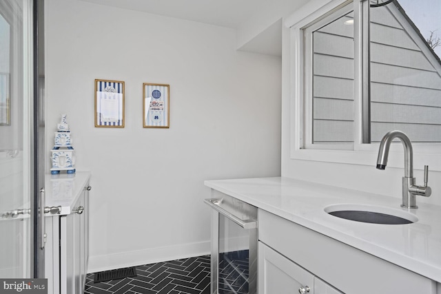 washroom with beverage cooler, a sink, and baseboards