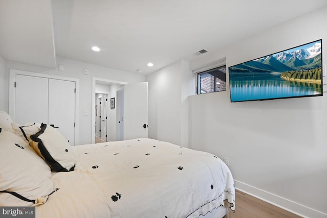 bedroom with recessed lighting, wood finished floors, visible vents, baseboards, and a closet