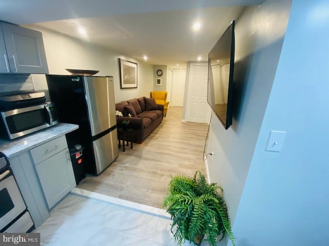 kitchen featuring light stone counters, light wood finished floors, stainless steel appliances, recessed lighting, and open floor plan