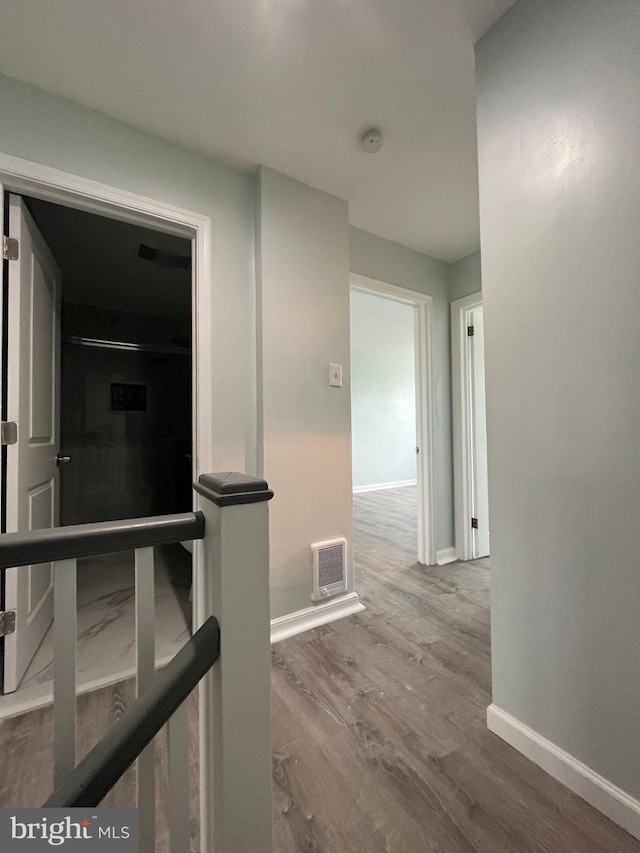 corridor with baseboards, visible vents, and wood finished floors