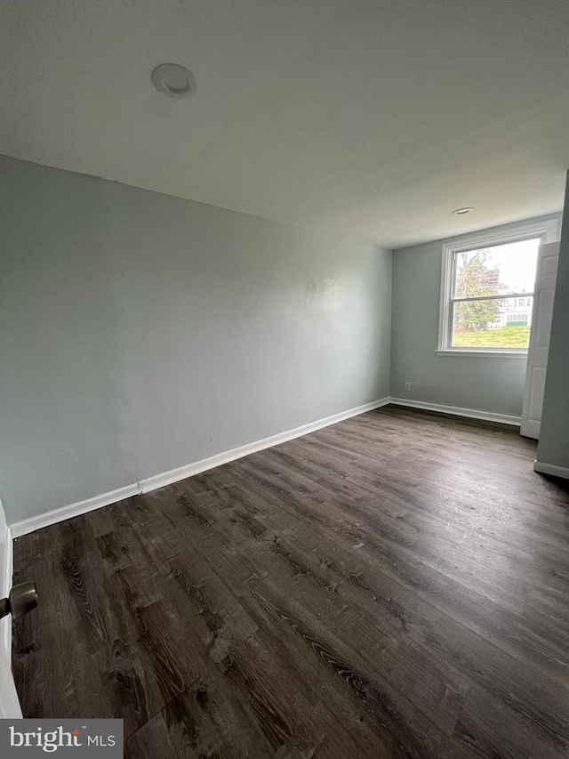 spare room featuring dark wood-type flooring and baseboards