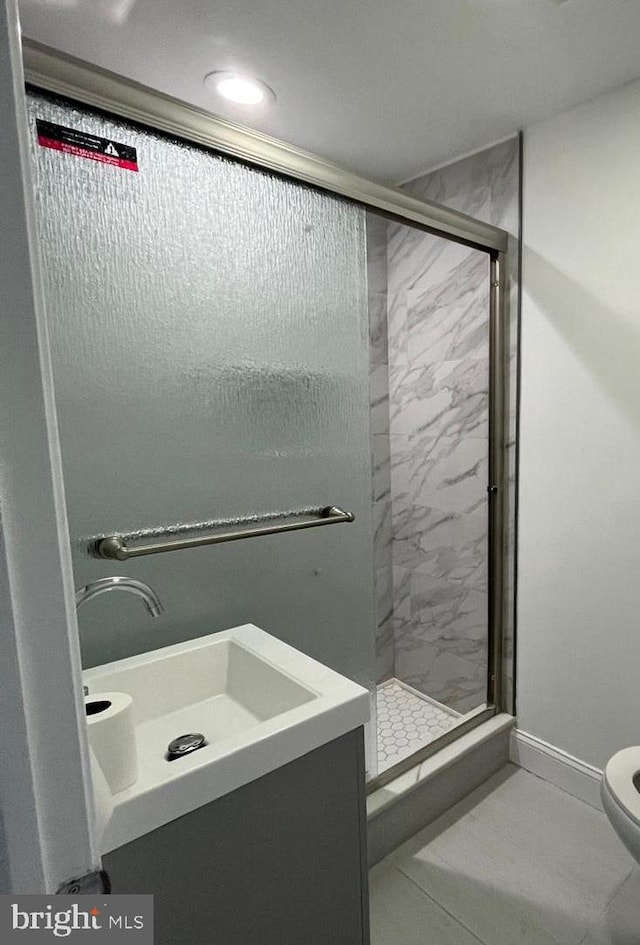 full bathroom with a stall shower, baseboards, vanity, and toilet