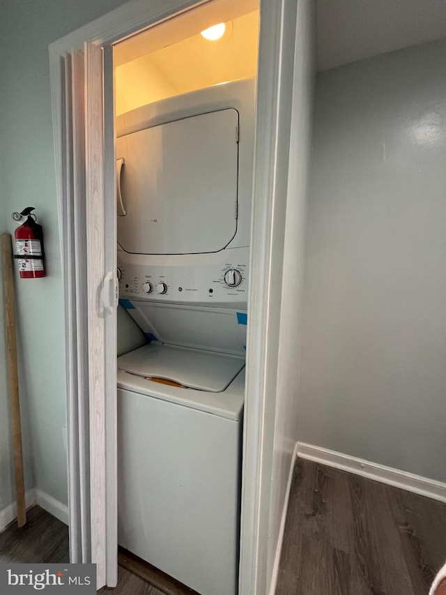 washroom featuring dark wood-style floors, laundry area, baseboards, and stacked washer / drying machine