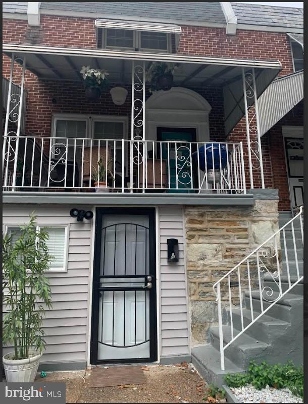 entrance to property with brick siding and a balcony