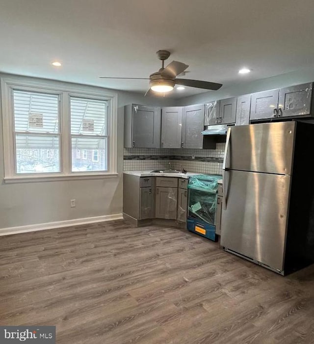 kitchen featuring light countertops, freestanding refrigerator, a sink, wood finished floors, and range