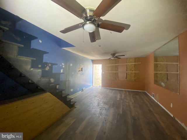 unfurnished living room with dark wood-style flooring, baseboards, and stairs