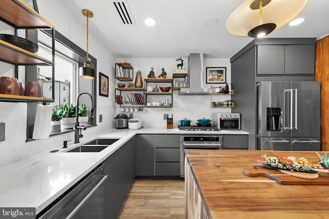 kitchen featuring a sink, open shelves, stainless steel appliances, and wall chimney exhaust hood