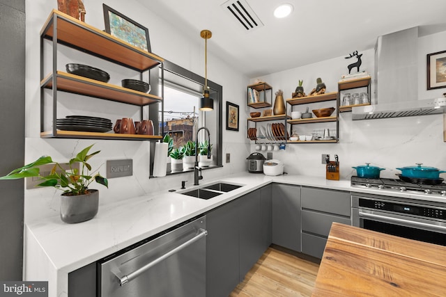 kitchen featuring visible vents, open shelves, wall chimney range hood, gray cabinets, and appliances with stainless steel finishes